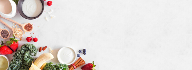 Wall Mural - Healthy food corner border. Smoothie making concept. Top view on a white marble banner background. Copy space. Fruit, yogurt, almond milk and an assortment of ingredients.