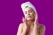 © Mountains Hunter - Beauty portrait of woman in white towel on head with a sponge for a body in view of a pink hearе on violet background.