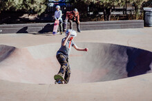 Kid Learning To Skateboard At The Skate Park.