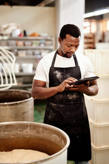 Poster - I log the times for every task. Cropped shot of a man using a digital tablet while working in a bakery.