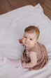 © Tatyana - Sweet  little 1-year-old daughter sitting on chair in grey dress.Portrait of Girl baby child on bed at home. Tenderness and love, sweetness. Lovely family indoors.Serious baby portrait indoors