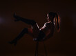 High contrast silhouette picture of sexy and passionate young woman sitting on a high chair and posing with her legs up