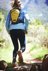 Sticker - Putting the miles behind her. Rearview shot of a woman out for a trail run.