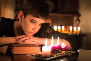 Vintage looking woman reading antique book under the candle light at night