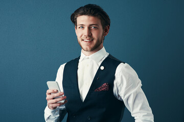 Aufkleber - Staying in touch via text. Studio shot of a handsome young businessman sending a text message against a blue background.