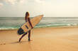 © Mary - blonde surfing girl walking along a sandy beach with a dock for surfing on the background of a tropical wave