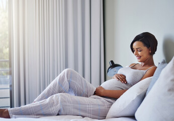 The big day is almost here. Shot of a pregnant young woman relaxing on the bed at home.