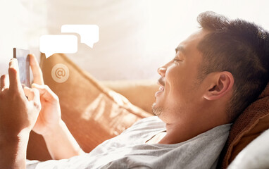 Poster - The easiest way to stay in touch with his friends. Shot of a happy young man using his cellphone while lying on the couch at home.