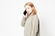 © garage38 - 白い背景の前に立ってスマホを使う若い女性