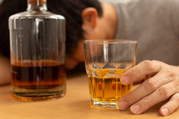 Alcohol addicted man sleeping at the table. Sad depressed male adult having troubles with alcohol.