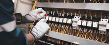 Electricity And Electrical Maintenance Service, Engineer Hand Holding AC Voltmeter Checking Electric Current Voltage At Circuit Breaker Terminal And Cable Wiring Main Power Distribution Board.