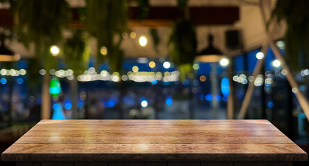 Empty wooden table top with lights bokeh on blur restaurant background.