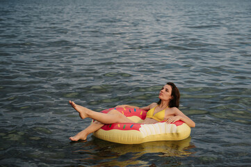 Wall Mural - slender girl swims on an inflatable circle in sea in summer on vacation