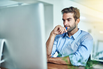 Aufkleber - Thinking of some bright ideas. Shot of a young businessman working on a computer in an office.