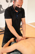 © unai - An athletic man receiving a recovery massage by a physiotherapist on a stretcher, detail of the therapeutic passage and osteopathy, vertical photo