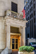 New York Stock Building Exchange golden colored Building Entrance with American Flag above during winter, vertical