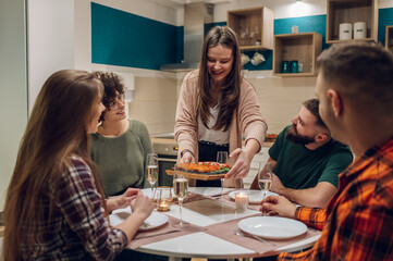 Group of friends enjoying dinner while sitting at the kitchen table together