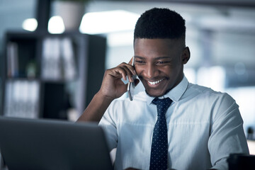 Poster - Its turning into one successful night. Shot of a young businessman talking on a cellphone while working on a laptop in an office at night.