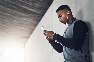 Wall Mural - Im right in the middle of my workout. Cropped shot of a handsome young man sending a text while exercising outside.