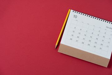 close up of calendar and pencil on the red table background, planning for business meeting or travel planning concept