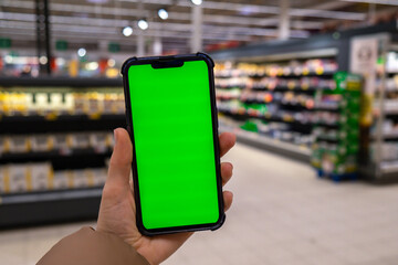 Chroma key. Close up of woman hand holds smart phone vertical with green screen at shopping mall store. Shopping center. Department store. Shopping online. Gadgets template