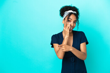 Wall Mural - Young latin woman isolated on blue background pointing to the side to present a product and whispering something