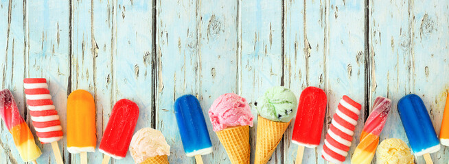 Poster - Variety of colorful summer popsicles and ice cream treats. Top view bottom border on a rustic blue wood banner background. Copy space.