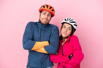 Wall Mural - Young cyclist caucasian people isolated on pink background making doubts gesture while lifting the shoulders