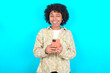 © Roquillo - young girl with afro hairstyle wearing floral shirt over blue background taking a selfie  celebrating success