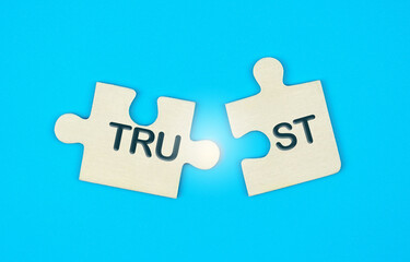 two disconnected puzzle pieces with the word trust on a blue background. broken trust, to violate ag