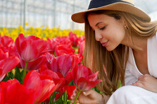 Happy Woman With Straw Hat Smelling Tulips On Farm