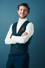 Poster - Being a businessman looks good on me. Studio shot of a handsome young businessman standing with his arms crossed against a blue background.