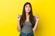 © luismolinero - Young Brazilian woman isolated on yellow background with fingers crossing and wishing the best