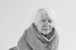 monochrome portrait of senior woman in scarf freezing cold at home. Health care, crisis, oldness concept