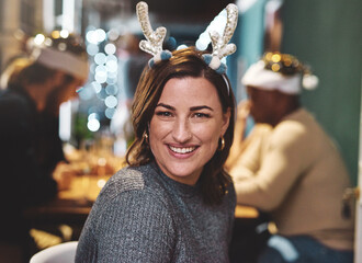 Wall Mural - its a cheerful evening with us. Portrait of a cheerful young woman wearing a festive hat at home during christmas time.