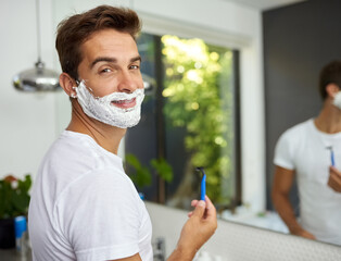 The cream before its all gone. Cropped shot of a handsome man about to shave his beard in the bathroom at home.