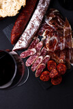 Fototapeta Uliczki - Spanish snack with chorizo, salchichon, jamon, fresh baguette and a glass of red wine.