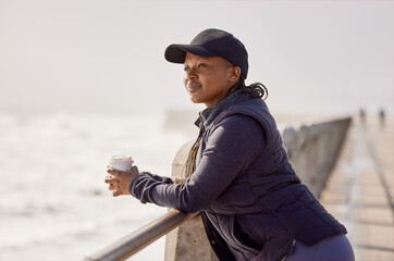 Wall Mural - Good coffee and good views. Shot of a young woman enjoying a cup of coffee by the ocean.