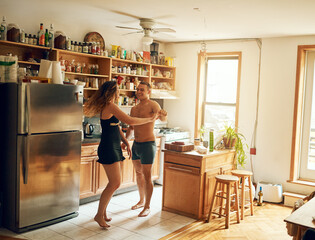 Wall Mural - Fill a house with love and make it a home. Shot of a happy young couple dancing in the kitchen at home.