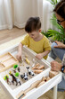 Montessori material. Little boy with his mom explores the farm animals in the game.