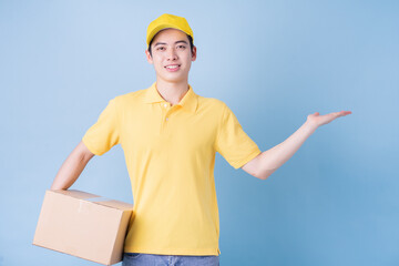 Wall Mural - Image of young Asian delivery man on blue background