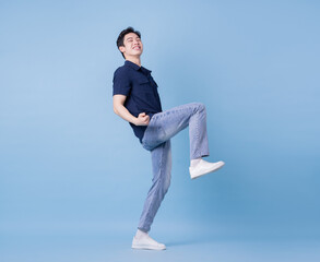 Wall Mural - Full length image of young Asian man posing on blue background