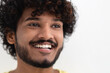 © kucherav - Portrait young happy positive Indian man with white teeth and curly hair smiling broadly on white background, copy space, good mood concept
