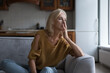 © fizkes - Frustrated lonely mature 50s woman looking away, sitting on sofa at home touching face. Sad lady thinking over health problems, suffering from apathy, depress disorder, memory loss, dementia