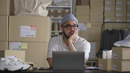 Wall Mural - Successful Asian businessman. Smiling young man online seller taking note of orders from customers. Dropshipping business owner working in his store warehouse.