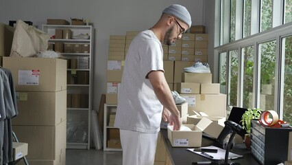 Wall Mural - Asian man business owner working, packing the order for shipping to customer. Male entrepreneur packaging box for delivery in store warehouse.