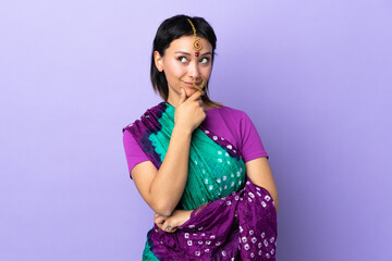 Wall Mural - Indian woman isolated on purple background thinking an idea while looking up