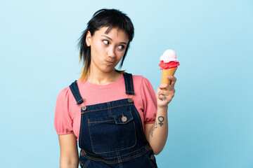 Wall Mural - Young Uruguayan girl holding a cornet ice cream over isolated blue background with sad expression