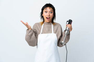 Wall Mural - Chef Uruguayan girl using hand blender over isolated white background with surprise facial expression