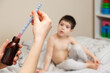 © Zarina Lukash - The pediatrician or mother types in a measuring syringe the medicine for cough or temperature syrup for the child